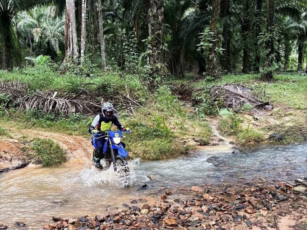 Enduro rider splashing through clear mountain stream on a dirt bike tour in Krabi