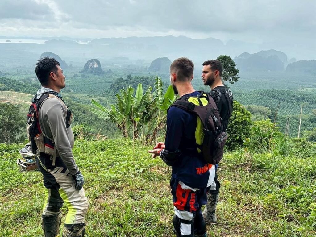 Motorcycle tour riders taking a rest to enjoy mist-covered karst mountain views in Krabi