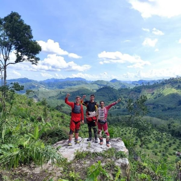 Dirt bike adventure tour riders celebrating at a scenic Krabi mountain summit viewpoint
