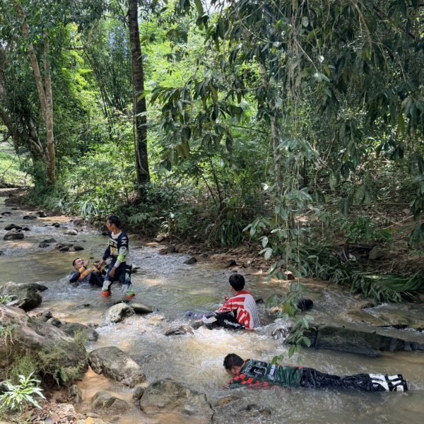 Dirt bike riders cooling off and swimming in a natural jungle river during Krabi tour