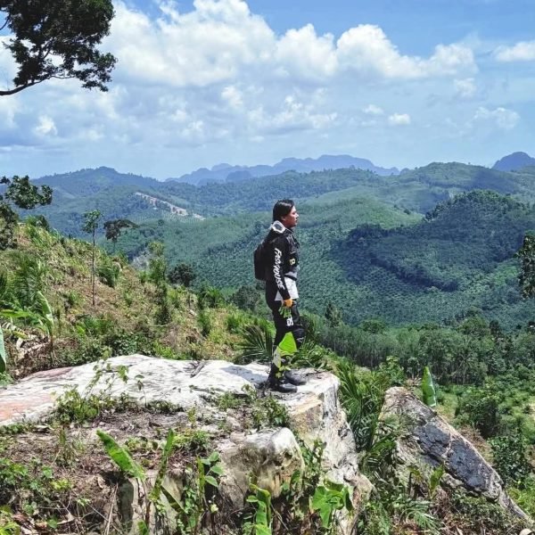 Enduro rider admiring stunning Krabi landscape from high mountain cliff