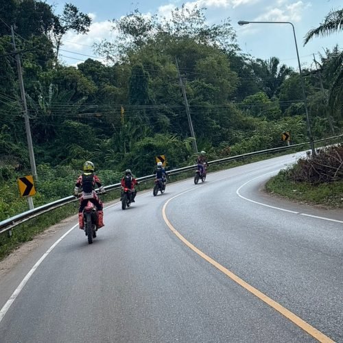 Motorcycle touring riders cruising on winding scenic road in Krabi