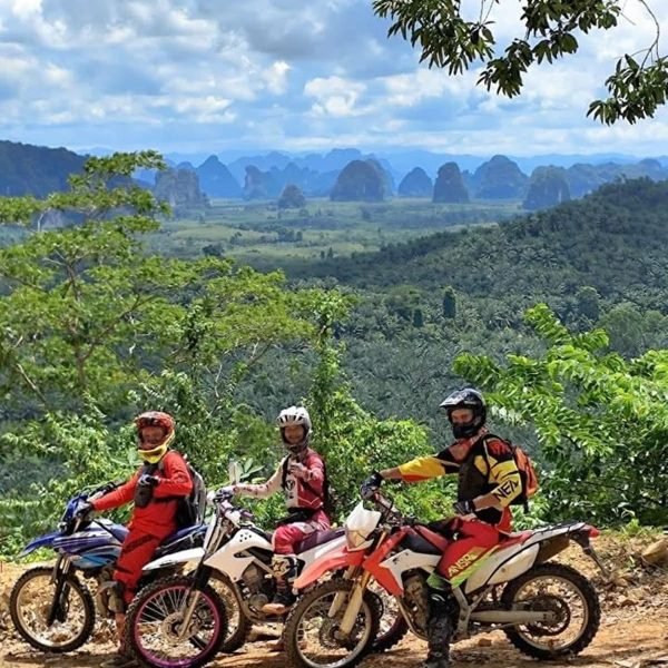 Enduro motorbike riders taking a break overlooking breathtaking panoramic karst mountains in Krabi