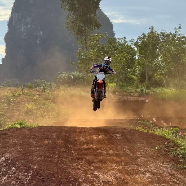 Motocross rider jumping on dirt track with limestone mountain background at Krabi Dirt Ride Experience
