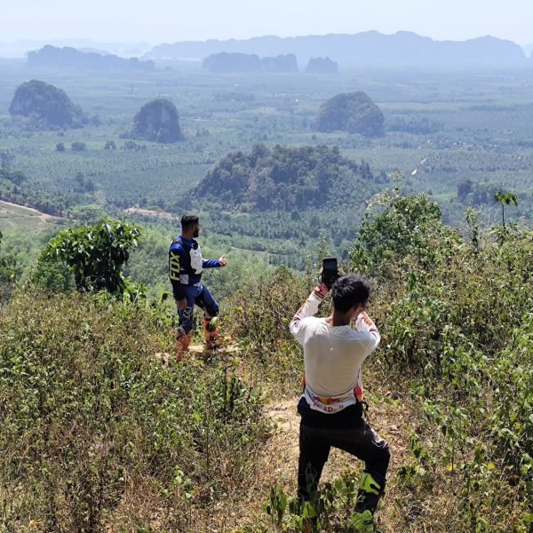 Touring riders photographing scenic karst landscape from high Krabi mountain summit